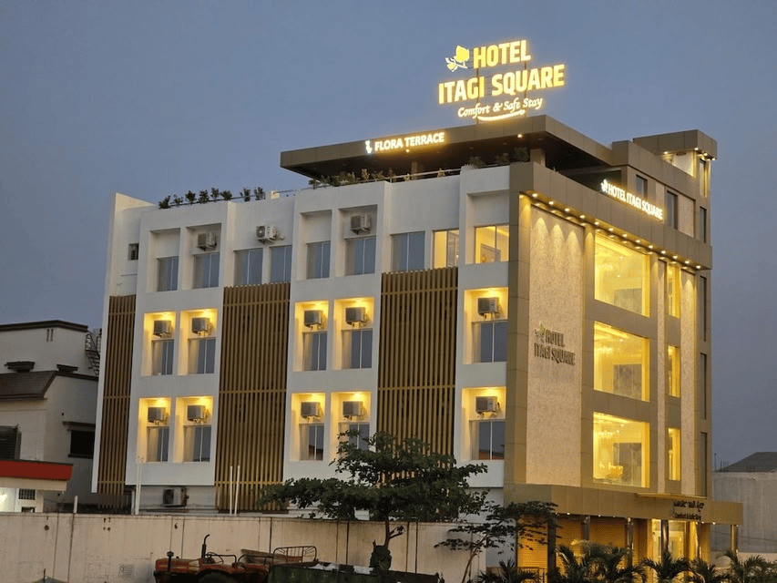 Hotel Itagi Square entrance framed by palms, with warmly lit doors and steps